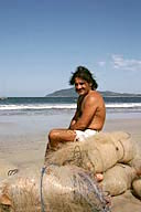 Costa Rica: Playa Tamarindo, local fisherman on beach sitting on fishing nets, December