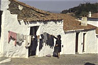 Portugal: Monsaraz, woman with black hat tending laundry on line next to whitewashed house
