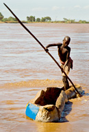 Dassanech man poling his dugout canoe used as a ferry at Omorate