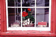 Maine: Camden, window with antique folk art and geraniums