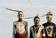 Nyangatom village dance, men wearing traditional body paint and ostrich feather headdresses