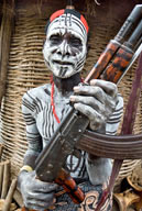 Duss community, a Karo man holding rifle in front of granary